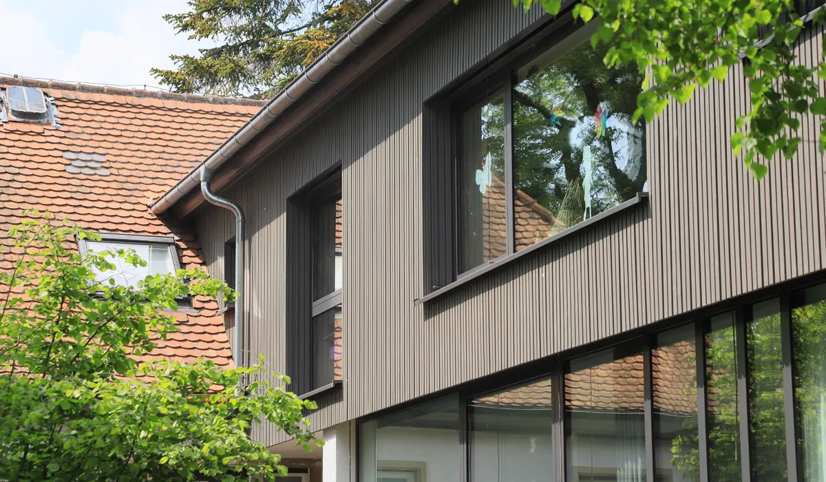 Seitenansicht eines modernen Einfamilienhauses mit einer Kombination aus Putz und hochwertigen Holzfassadenelementen